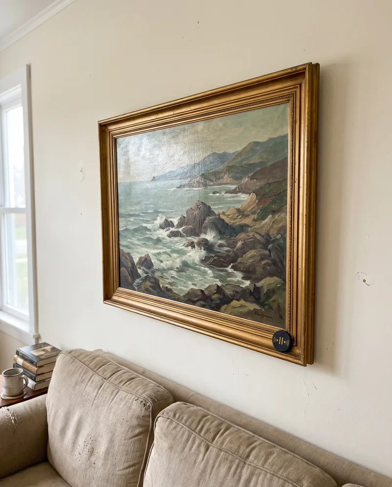 A framed seascape painting on a living-room wall, a Seal on the frame